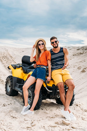 young couple leaning back on an atv in the desert