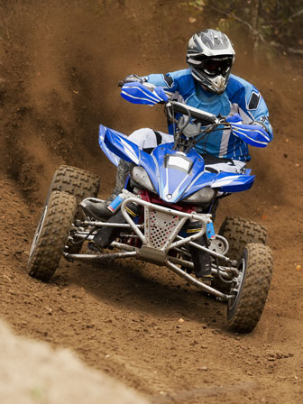 quad driver racing on a dirt trail